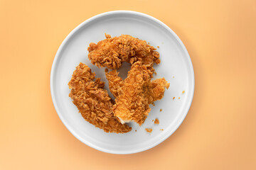 Flat lay or top down view cooked fried crispy fried chicken on a white round ceramic plate with...