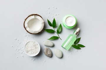 Coconut with jars of coconut oil and cosmetic cream on colored background. Top view. Free space for your text. Natural spa coconut cosmetics and organic treatment concept Coconut Spa composition