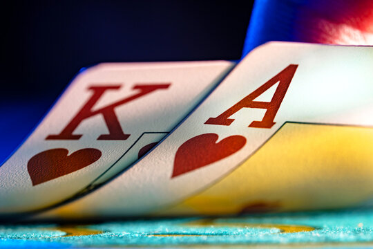 A pair of king and ace of hearts suit playing cards on a blue background of a gaming table in a casino. Close up of playing cards for gambling, poker, blackjack, texas hold'em. Gambling in the casino.