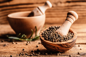 Black pepper in wood bowl on wooden table. Spices on desk. Organic spice dry peppercorn. © Zedspider