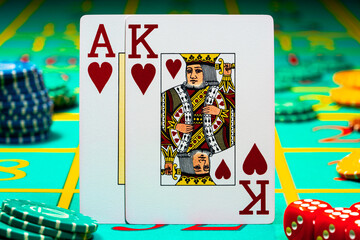 A pair of king and ace of hearts of playing cards on green background of a gaming table in a casino. Close up of playing cards, chips and dice for gambling, poker, blackjack, texas hold'em.
