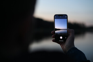 hand holding smart phone and taking photo of beautiful sunset