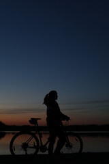 Obraz premium Silhouette of woman with mountain bike on colorful blue sky sunset background. Active outdoors lifestyle
