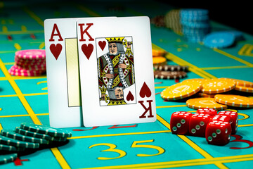 A pair of king and ace of hearts of playing cards on green background of a gaming table in a casino. Close up of playing cards, chips and dice for gambling, poker, blackjack, texas hold'em.