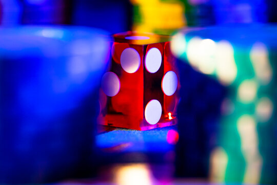 Red gambling dice on a blurred background of blue casino chips. Dice for playing poker or craps. The concept of gambling, betting, money, risk, winning. Online casino. Close up.