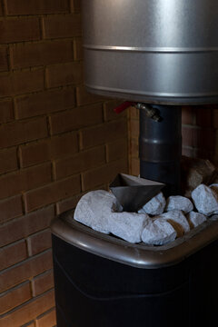Hot crushed bath stones lie on top of on stove in steam room in sauna