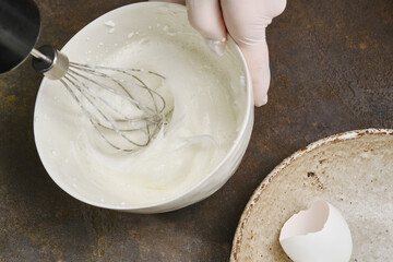 Kneading and whisking the liquid eggs with a mixer. Process of cooking meringue in a white bowl. Whipping cream with a whisk. Shallow depth of field