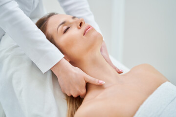 Fototapeta na wymiar Young nice woman having face massage in spa