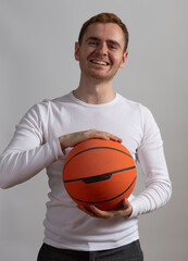 Contemporary young man poses in studio.with a basketball.