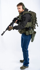 airsoft player in full gear with weapons series GG RK74 fire. a man in an outfit, in headphones, a bulletproof vest, with a backpack and a belt. White background.