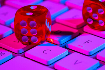 Keyboard computer and a red dice illuminated with pink light. The concept of gambling, online...