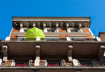 Biel, Switzerland - Mai 11, 2022: Low angle view of old historic house in Biel with a green sunny umbrella on the balcony - obrazy, fototapety, plakaty