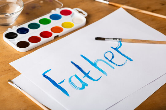 Painted word father with watercolors on white paper. Father's Day and family concept.