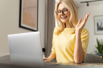 Happy young nice woman looking at the laptop screen, holding video call meeting conversation, discussing working issues, passing job interview from home, distant communication concept