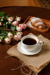 Close up view of coffee cup, croissant on background