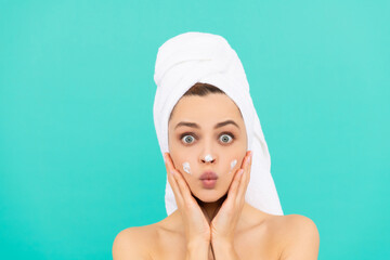 amazed young girl apply face cream on blue background