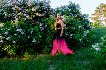Obraz na płótnie Canvas Lady in a summer dress on a near the bushes.