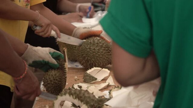 Peeling durian fruit with a knife, close up, slow motion.