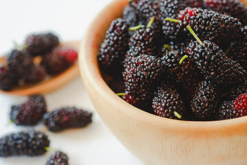 Close-up Black mulberry in a wooden cup is a healthy berry with a sweet and sour taste.