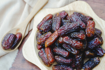 Close-up Dates in a wooden dish are dried, brown fruits that can be eaten whole with the skin and have a very sweet taste.
