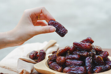 Hand holding a date palm in a wooden cup It is a brown dried fruit that provides high energy and...