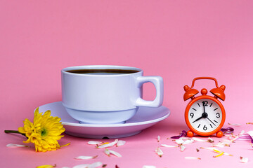 White coffee cup with alarm clock set at 8 o'clock on pink background.