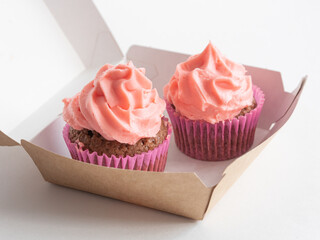 Cupcakes with a pink cream cap in an open paper box. Baking to go.