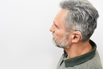 Hearing loss treatment concept at older people. Senior man with hearing aid behind the ear can hear sounds