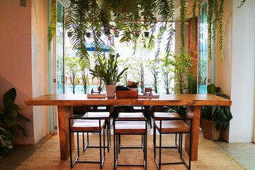 A long table made of logs has plants on it and there are vines hanging down from the roof