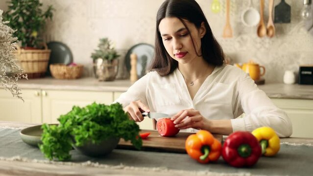 Portrait of attractive cheerful woman cooking vegetables on dometic kitchen in slow motion. 