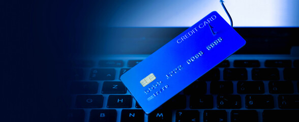 Phishing Credit Cards - Piles of credit cards with fish hook on computer keyboard. Dark cyber...