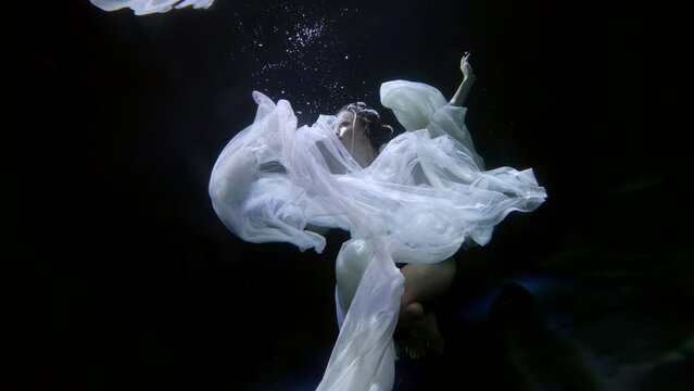 Surreal mermaid underwater on the surface. A majestic female aquatic creature. art installation under water