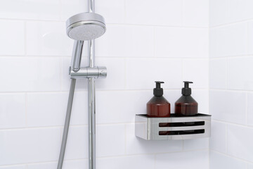 Shower head and  bathroom shelf with toiletries on background of white wall with metro ceramic...
