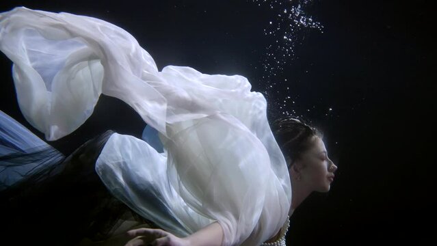 Surreal woman underwater in a dress. Art installation mermaid as in a fairy tale