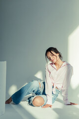 Young woman in ripped jeans and shirt sits with closed eyes.
