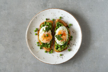 Toasts with green peas and eggs on a concrete background. Homemade healthy pea toast