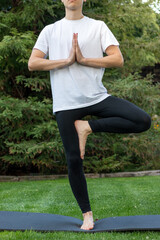 Unrecognizable man in yoga tree pose for relaxation and meditation as an anti-stress technique breathing clean air