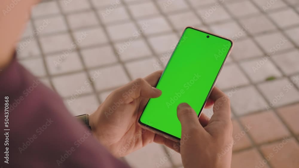 Aufkleber 10 bit shot with hands of a man writing-texting on a smartphone with green screen in the day time