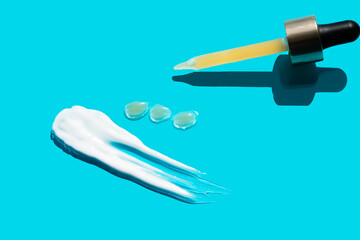 Pipette with dose of fluid hyaluronic acid on blue background. cosmetic concept. flat lay.