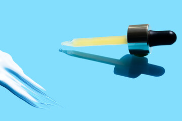Pipette with dose of fluid hyaluronic acid on blue background. cosmetic concept. flat lay.