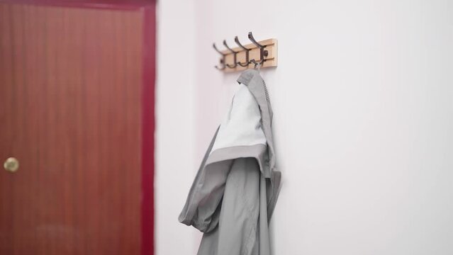 Person hand hang gray raincoat on hook 4K