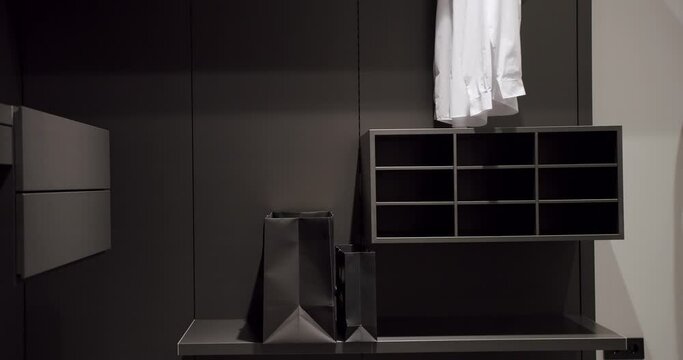 Black wardrobe with Sliding Black Doors. Luxury Bedroom With Walk In Closet. Dressing room with shirts. Elegant Wooden Built Walk In Closet Decoration. Luxury Dressing Room. Modern Sliding Doors.