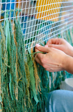 weaving a camouflage uniform for a sniper.Ukrainian volunteer girl weaves the basics for a camouflage coat for a soldier