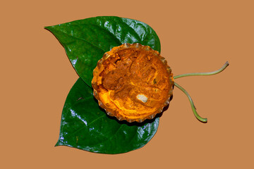 Yellow turmeric paste kept into a bronze bowl placed on top of two betel leaves