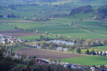 Fototapeta na wymiar Aerial view of valley with forest, agricultural fields and pond seen from local mountain Uetliberg on a blue cloudy spring day. Photo taken April 14th, 2022, Zurich, Switzerland.
