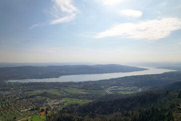 Obraz premium Panoramic view from local mountain Uetliberg with Lake Zürich and Swiss Alps in the background on a blue cloudy spring day. Photo taken April 14th, 2022, Zurich, Switzerland.