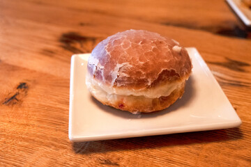 Fried donut on a white plate on a wooden table. delicious pastries