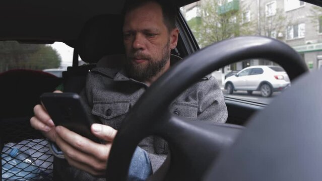 a man driving a car is resting with a phone in his hands, part-time job in a taxi, a driver waiting for an order
