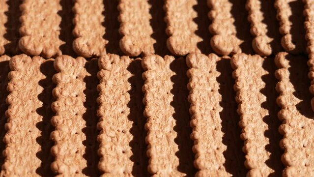Closeup view 4k stock video footage of tasty crispy brown chocolate biscuits cookies isolated. Abstract food video background with dark contrast shadows of sun light on surface of cookies laying