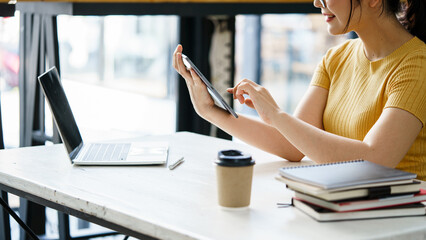 An asian woman sitting at meeting table and looking at laptop with smile. Employee waiting for meeting hour.